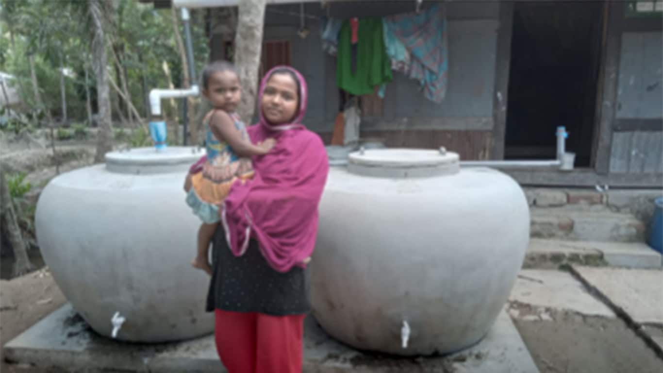雨水貯留タンクの前で微笑む現地の子どもたちの写真